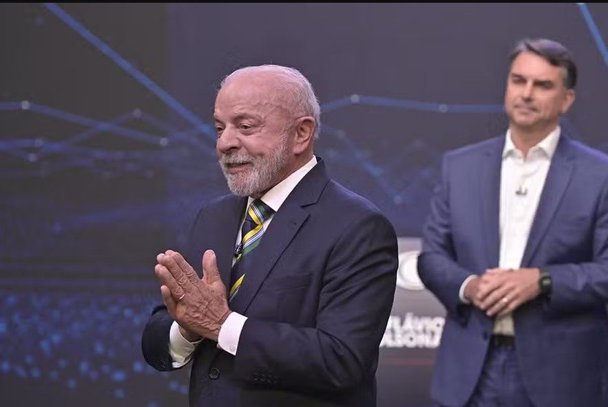 Flávio Bolsonaro atrás de Lula durante o debate da TV Bandeirantes.